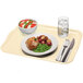 A Cameo yellow Cambro tray with food, a glass of water with ice and lemon, and a bowl of tomato and basil salad on it.