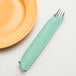 A fork in a Fresh Mint Green Creative Converting dinner napkin next to a plate.