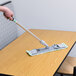 A hand holding a Unger mop cleaning a table