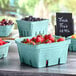 A table with several green molded pulp baskets filled with berries.