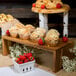 A Tablecraft Acacia Wood 3-piece Cascade Riser set holding a tray of muffins and strawberries on a table.