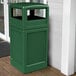 A Forest Green Commercial Zone PolyTec waste container and dome lid on a wooden porch.
