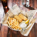 Fish and chips in American Metalcraft newspaper deli wrap on a table.