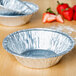 A close up of a D&W Fine Pack foil pie pan with strawberries inside.