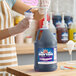 A gallon jug of Carnival King grape snow cone flavoring syrup with a pump dispenser.