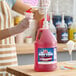 A gallon jug of Carnival King cherry snow cone flavoring syrup with a pump dispenser.