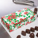 A 1 lb. Poinsettia candy box next to chocolate candies.