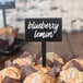 A table with a group of muffins with American Metalcraft mini rectangle chalkboard picks with a sign that says blueberry lemon muffins.