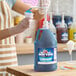 A gallon jug of Carnival King blue raspberry snow cone flavoring syrup with a pump dispenser.
