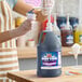 A gallon jug of Carnival King grape snow cone flavoring syrup with a pump dispenser.