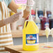 A large yellow gallon jug of Carnival King banana snow cone flavoring syrup with a pump dispenser.