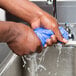 A person washing their hands with a blue cooling towel.