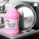 A pink bottle of Noble Chemical Pan Pro concentrated liquid detergent on a counter in a professional kitchen.