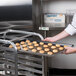 A person using a Vollrath Wear-Ever bun pan to hold cookies.