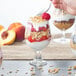 A hand spooning yogurt and strawberries into a Libbey Belgian beer/tulip glass.