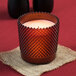 A Sterno flameless wax candle in a red hobnail glass container.