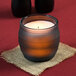 A Sterno flameless wax filled glass lamp on a table in a candle holder.