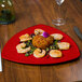 A red GET triangular melamine plate with shrimp and a glass of wine on a table.