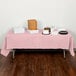 A table with Classic Pink Tissue / Poly Table Cover on it with food.