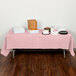 A table with Classic Pink Creative Converting table cover and food on it.