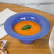 A peacock blue melamine bowl of soup on a table.