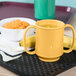 A yellow GET Tropical Yellow Two Handle Mug on a tray with a bowl of porridge and a banana.
