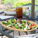 A GET Osslo latte oval melamine platter with a salad on a table outside.