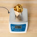 An Edlund digital portion scale with french fries on a stainless steel platform.