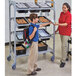 A woman and a boy in a school kitchen using a Cambro Camshelving® Flex Station to hold a box of food.