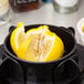 A black bowl with lemons cut into wedges using a Chef Master 8 Section Citrus Wedge Cutter.