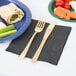 A black velvet 1/4 fold luncheon napkin with a fork and knife on a white table.