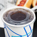 A translucent plastic lid with a straw slot on a Choice paper cold cup.