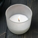 A Sterno PetiteLites white wax candle in a glass container on a table.