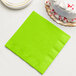 A Fresh Lime Green Creative Converting paper napkin on a table with a slice of white cake.