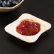 A wooden Eco-gecko palm leaf bowl with red jelly and a wooden spoon.