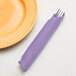 A Luscious Lavender purple Creative Converting paper dinner napkin with a fork in it next to a plate.