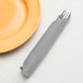 A fork and knife in a Shimmering Silver Creative Converting paper dinner napkin.
