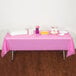 A table with a Candy Pink Creative Converting plastic tablecloth and food on it.