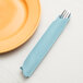 A fork and knife in a Creative Converting pastel blue paper dinner napkin.