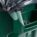 A green Rubbermaid BRUTE commercial trash can with a black lid over it.