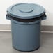 A Rubbermaid grey plastic trash can with a black lid.