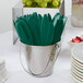 A silver bucket filled with green plastic knives.