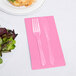 Creative Converting Candy Pink 3-ply Guest Towel with fork and knife on a table with salad.