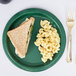 A Creative Converting hunter green paper plate with a sandwich and macaroni on it.