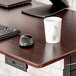 A black Luxor electric standing desk with a keyboard, mouse, and coffee mug on it.