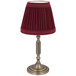 A red lamp shade with pleats on a Sterno La Rue oil bronze metal lamp base.