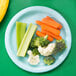 A Creative Converting pastel blue paper plate with a group of carrots and broccoli.