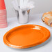 A Sunkissed Orange paper platter on a table with white utensils.