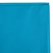 A turquoise blue plastic table cover in packaging with a zipper.