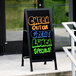 A black A-Frame sidewalk sign with a black and white sign that says "Check Out Our Great Lunch Specials"